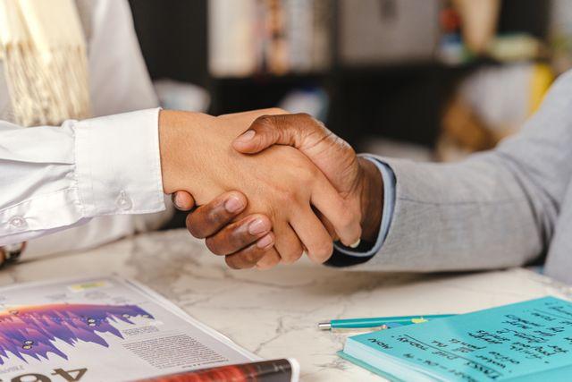 two people shaking hands over a desk